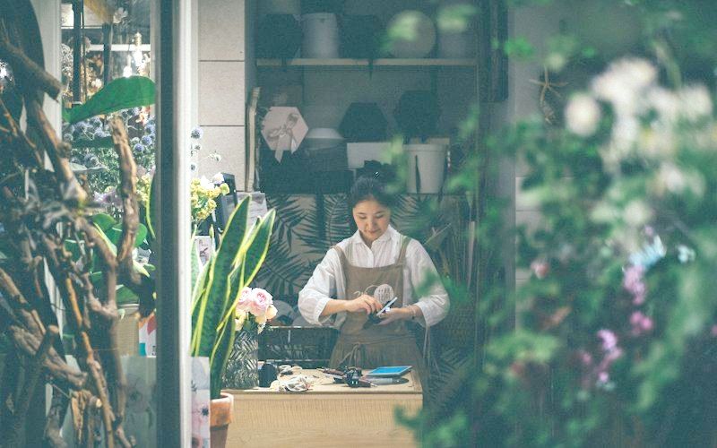 植物に囲まれた花屋で作業する店主